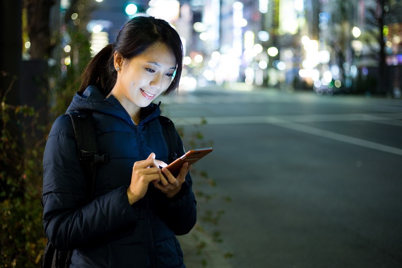 Woman use of cellphone and standing beside the road